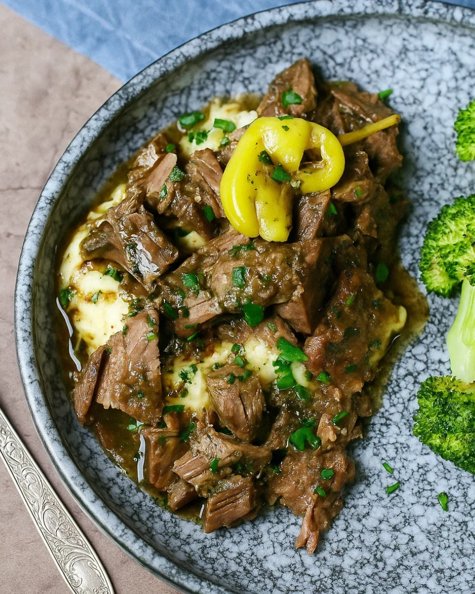 Tender Keto Mississippi Pot Roast served with a rich, savory gravy and pepperoncini peppers in a cast iron skillet.