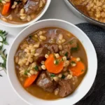 A bowl of hearty beef barley soup with vegetables and tender beef in rich broth.