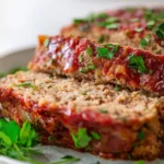 Moist turkey meatloaf topped with a smoky ketchup glaze, served on a plate.