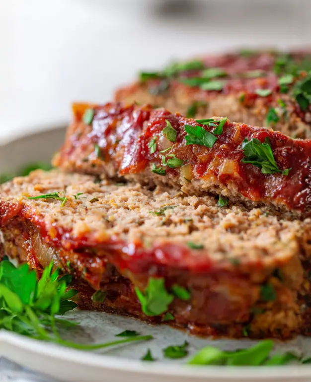 Moist turkey meatloaf topped with a smoky ketchup glaze, served on a plate.