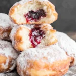 Homemade paczki, traditional Polish doughnuts filled with jam and dusted with powdered sugar.